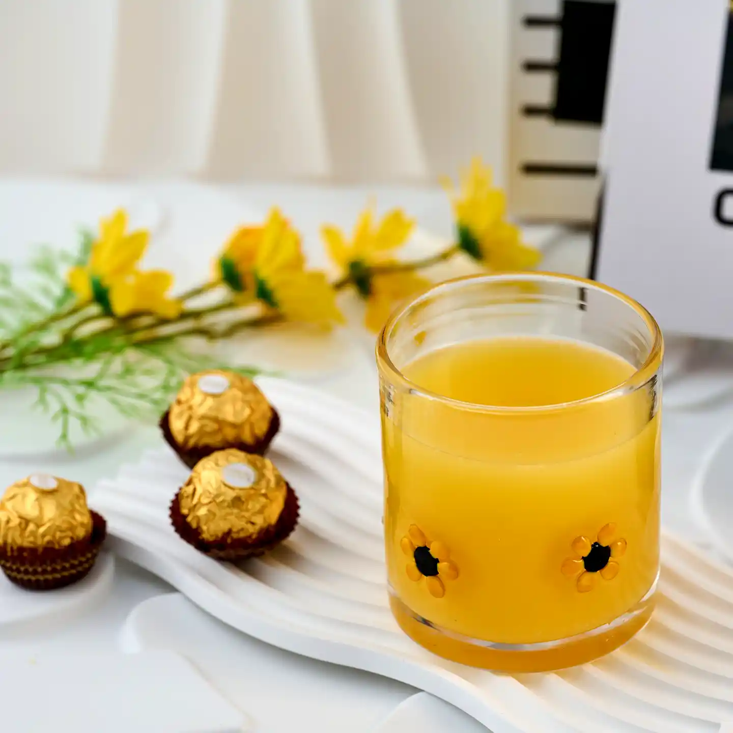 daisy double old fashioned glass full of orange juice in setting with chocolates.