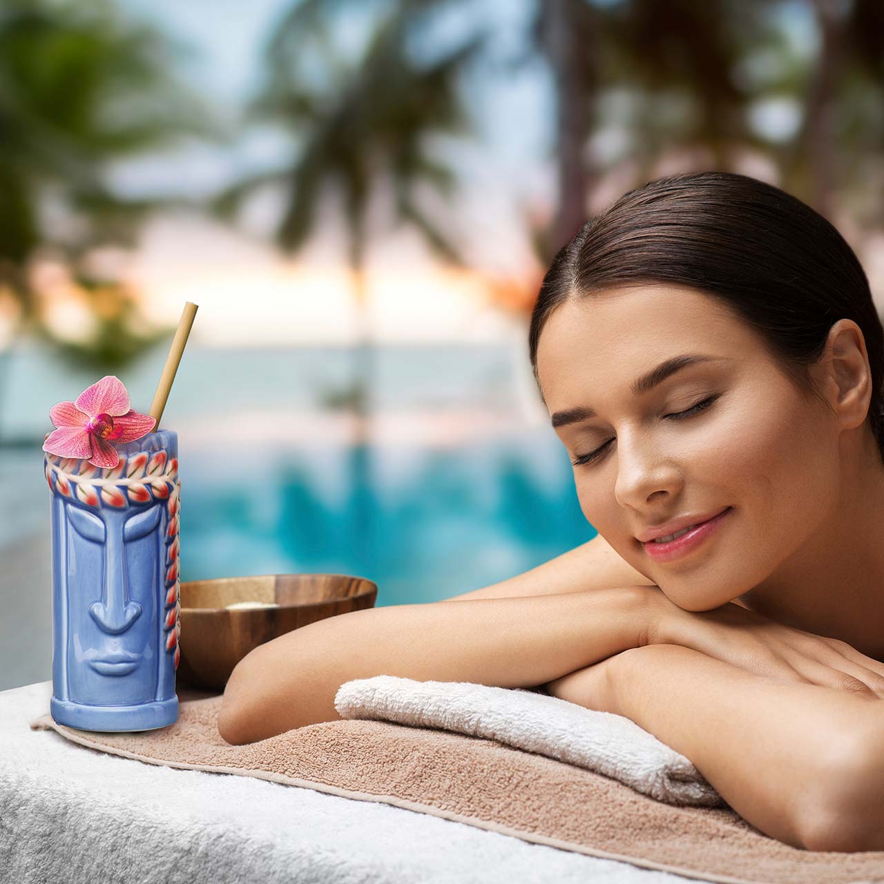 blue retro tiki glass with woman beach side getting a massage.